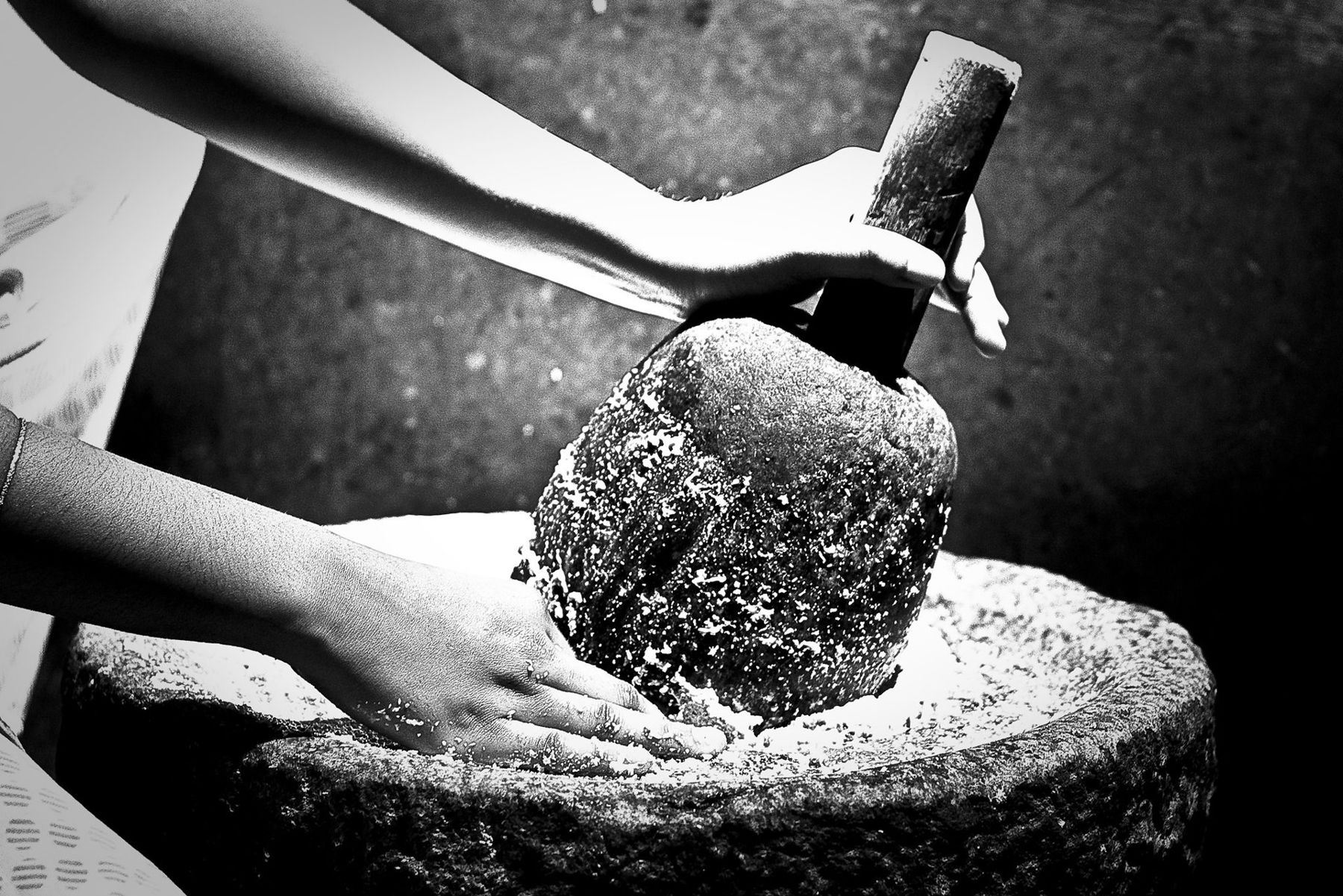 Hands working a traditional stone grinder